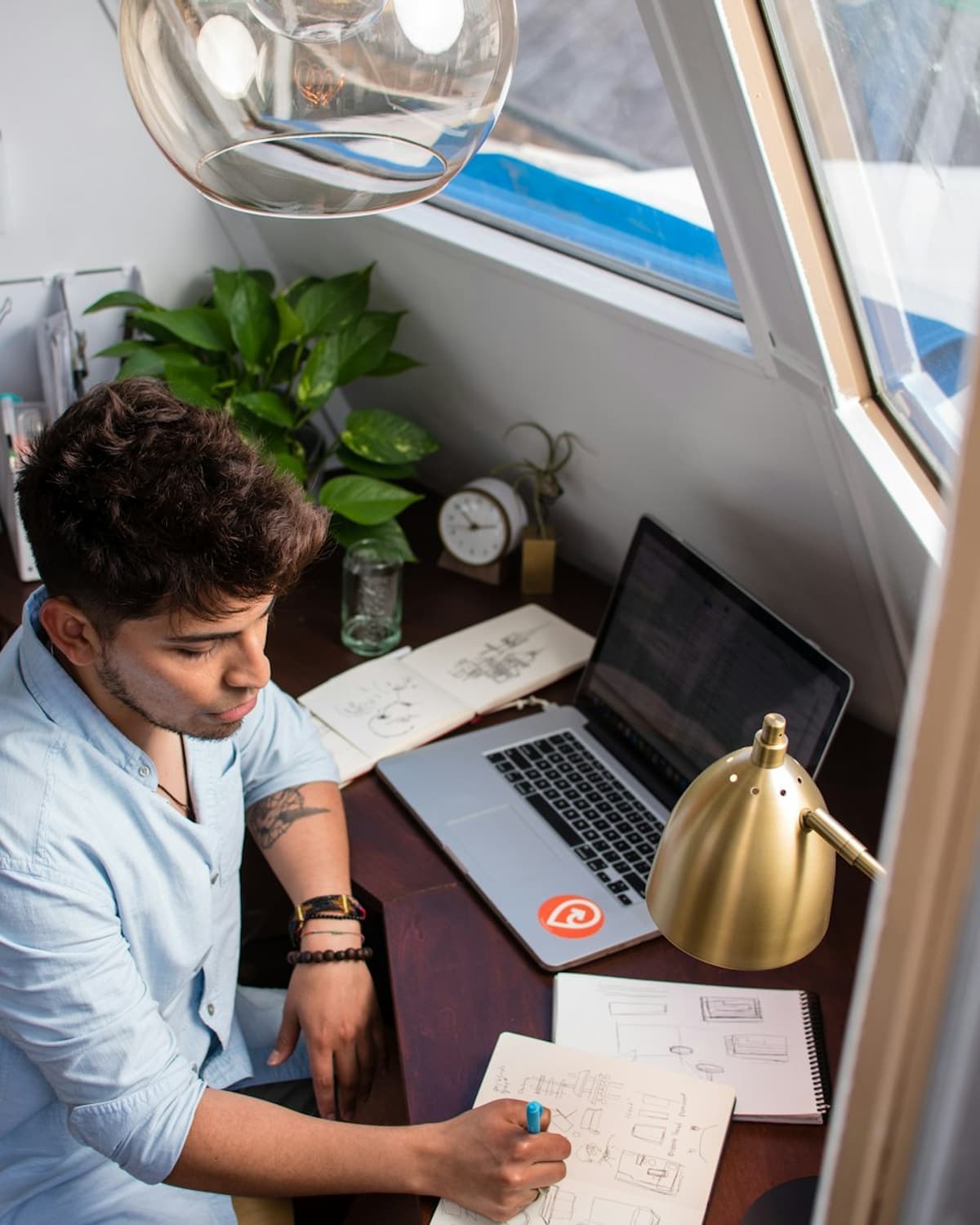 A worker writing notes beside a laptop